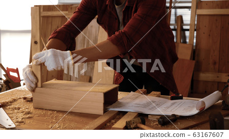 Carpenter fitting pieces of boards together at site. 63167607