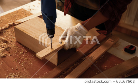 Carpenter using drill to screwing pieces of board at site. Carpenter using drill to screwing pieces of board at site. 63167608