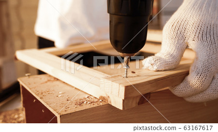 Close up of carpenter using drill to screwing wood board. 63167617