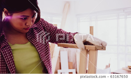Female carpenter fitting pieces of boards together at site. 63167650