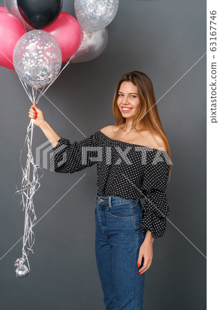 Young woman casual studio isolated on gray holding balloons Young woman casual studio isolated on gray holding balloons 63167746