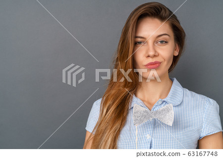 Young woman in dress studio isolated on gray with bow grining 63167748