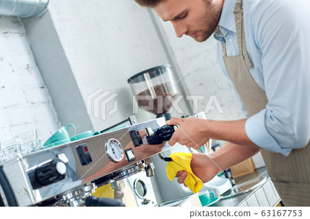 Young adult barista working in restaurant, cleaning professional coffee machine Young adult barista working in restaurant, cleaning professional coffee machine 63167753