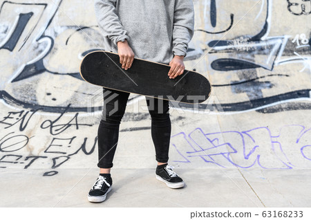 Close up of unrecognizable young man holding longboard or skateboard in the park. 63168233