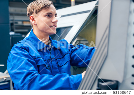 Young worker programming lathe machine in factory Young worker programming lathe machine in factory 63168647