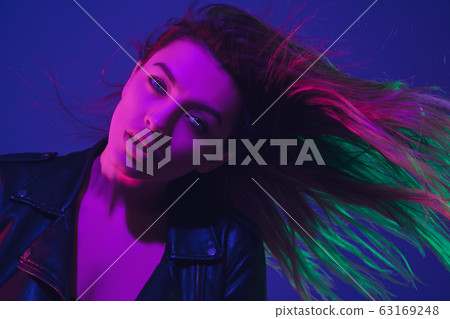 Caucasian woman's portrait isolated on blue studio background in neon light 63169248
