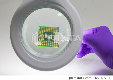 Hand in purple glove holding microchip with pair 63169705