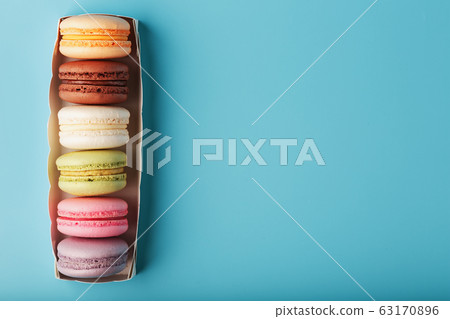 Multicolored French macaroni macaroni cookies in a white box on a blue background. 63170896
