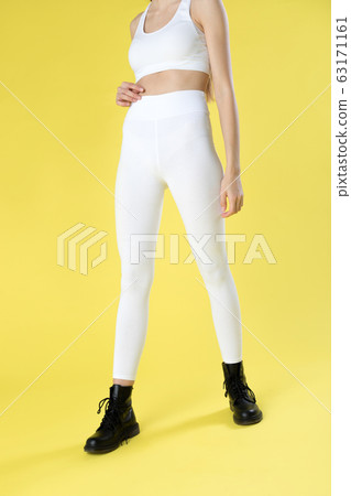 Young woman in white blank leggings and a crop top on a yellow background. Mock-up. 63171161