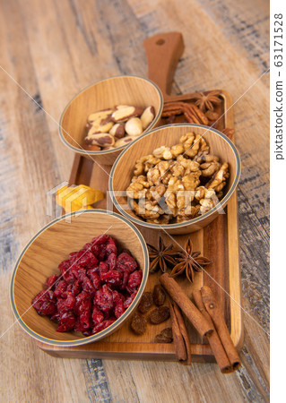 Mixed nuts and dried fruits in wooden bowl on wood background, copy space 63171528