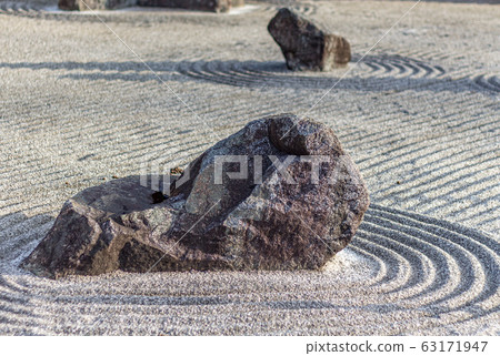 Japanese dry rock zen landscape garden, or karesansui, with raked sand or gravel to represent ripples in water. Kurikarafudoji temple, Tsubata, Japan. Japanese dry rock zen landscape garden, or karesansui, with raked sand or gravel to represent ripples in water. Kurikarafudoji temple, Tsubata, Japan. 63171947