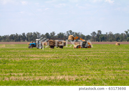 Tractor loading hay bales on truck agricultural works Tractor loading hay bales on truck agricultural works 63173698