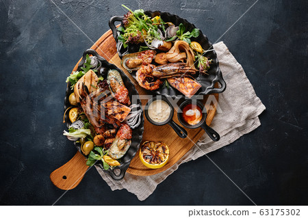 grilled seafood platter. Assorted delicious grilled seafood with vegetables. Grilled mixed bastards with pepper sauce and vegetables. Blue background grilled seafood platter. Assorted delicious grilled seafood with vegetables. Grilled mixed bastards with pepper sauce and vegetables. Blue background 63175302