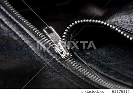 Iron zipper on a black leather jacket, needlework concept. Iron zipper on a black leather jacket, needlework concept. 63176315