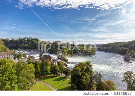 Rheinfall waterfall surround with green forest and blue sky background view from Neuhausen am Rheinfall railway station in switzerlad 63176932