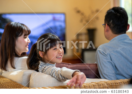 Image of three parents and children (father, mother, daughter) watching TV on the sofa Image of three parents and children (father, mother, daughter) watching TV on the sofa 63180343