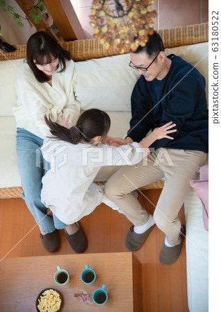 Image of three parents and children (father, mother, daughter) relaxing on the sofa 63180522