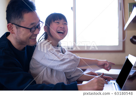 The image of a girl who touches the screen while laughing at her father teaching her computer 63180548