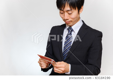 一個穿著西裝的男人帶著微笑看著存摺 63184190