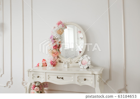 Vintage style boudoir table with round mirror and flowers. White bright room. Vintage style boudoir table with round mirror and flowers. White bright room. 63184653
