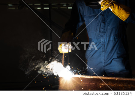 Metal welder working with arc welding machine. 63185124