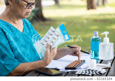 Stressed senior woman many daily expense with face mask,hand sanitizer,medicine because of epidemic,outbreak of Covid-19,elderly worry about wasting money,financial problem,family expenditure  63185164