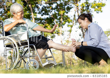 Asian senior woman suffering from leg cramp,female elderly stretching painful calf muscle,adult caregiver helping care the old people who have leg cramps injury,receiving a leg massage,health problem  63185165