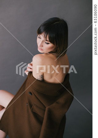 Woman in brown fashion coat on grey background. 63186090