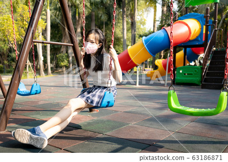 Asian child girl wearing protective mask in playground,girl prevent infection from Covid-19,dangerous situation,severe Coronavirus outbreak,risks,spread of Covid-19 virus is a serious global problem Asian child girl wearing protective mask in playground,girl prevent infection from Covid-19,dangerous situation,severe Coronavirus outbreak,risks,spread of Covid-19 virus is a serious global problem 63186871