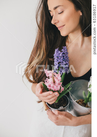 Woman hold pots with flowers on white background.  63186917