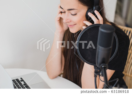 Woman blogger recording radio podcast in studio. 63186918