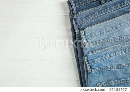 Different jeans folded on a white wooden 63188737