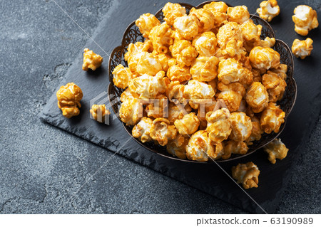 Popcorn in caramel glaze in a plate on a dark 63190989
