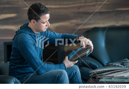 The man selects a new cover for the sofa from the color card sampler The man selects a new cover for the sofa from the color card sampler 63192039