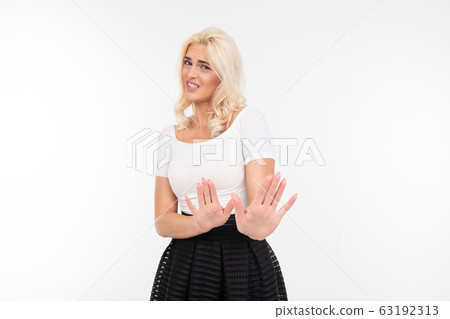 blond pretty girl in a white t-shirt and black skirt crossed her arms in front of herself on a white blond pretty girl in a white t-shirt and black skirt crossed her arms in front of herself on a white 63192313