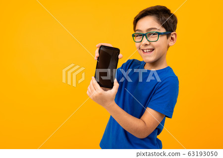 smart boy in glasses and a blue t-shirt holds the phone with the screen forward with a layout on a smart boy in glasses and a blue t-shirt holds the phone with the screen forward with a layout on a 63193050