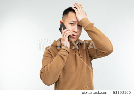 cute stylish asian male student talking on the phone on a gray studio background cute stylish asian male student talking on the phone on a gray studio background 63193100
