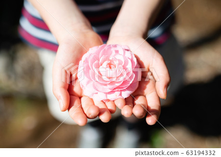 Child holding a pink flower 63194332