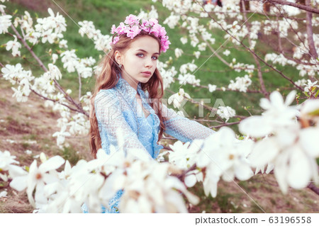 Attractive young girl among blooming magnolia Attractive young girl among blooming magnolia 63196558