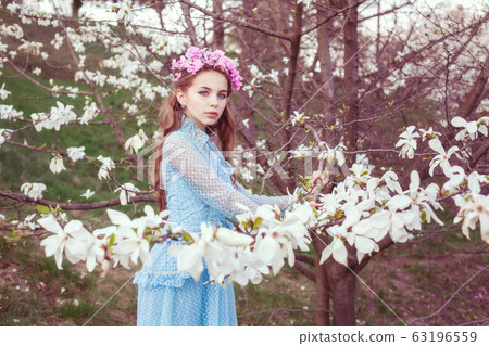 Beautiful young girl among blooming magnolia 63196559