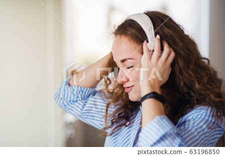 Young woman with headphones relaxing indoors at home. 63196850