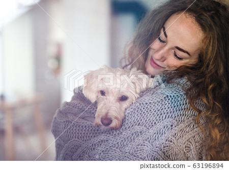 Young woman relaxing indoors at home with pet dog. Young woman relaxing indoors at home with pet dog. 63196894