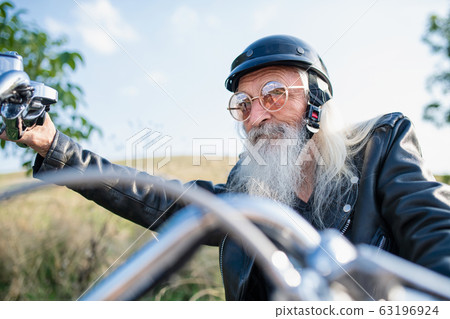 A senior man traveller with motorbike in countryside. A senior man traveller with motorbike in countryside. 63196924