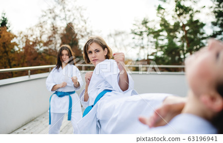 Group of young women practising karate outdoors on terrace. 63196941