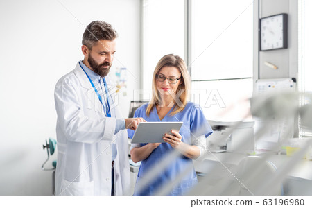 A dentist with dental assistant in modern dental surgery, working. A dentist with dental assistant in modern dental surgery, working. 63196980