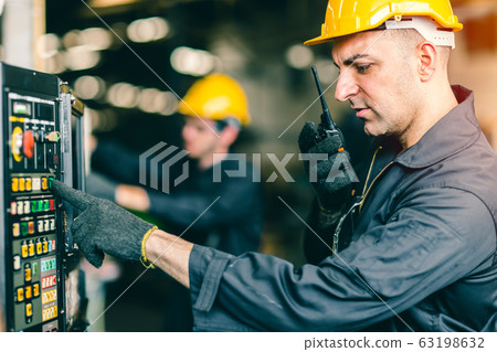 Professional labor worker engineer monitor at machine control panel and radio talking communication Professional labor worker engineer monitor at machine control panel and radio talking communication 63198632