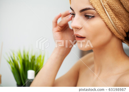 Cute girl puts patches under the eyes in the bathroom Cute girl puts patches under the eyes in the bathroom 63198987