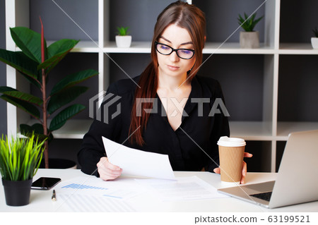 Young pretty woman working at the computer in the office and filling documents 63199521