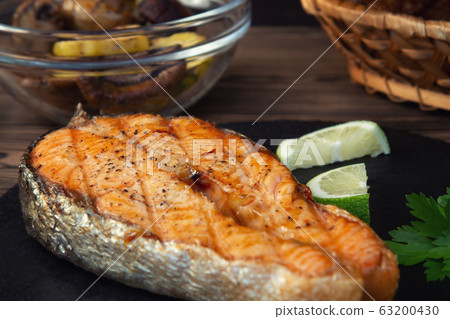 Grilled salmon steak on a black slate dish with parsley and lime 63200430
