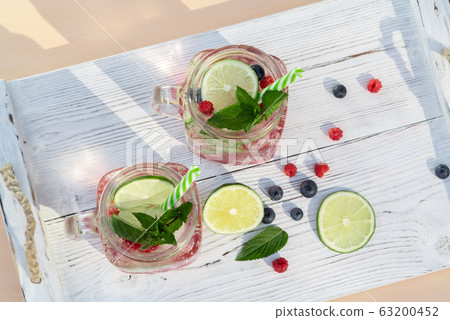 Homemade cold summer cocktail with mineral water, mint, lime, berry juice and fresh berries, top view Homemade cold summer cocktail with mineral water, mint, lime, berry juice and fresh berries, top view 63200452